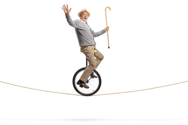 istock Elderly man riding a mono-cycle on a rope and holding a walking cane 1164347293