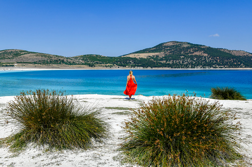 Woman in red dress walking on the beach.