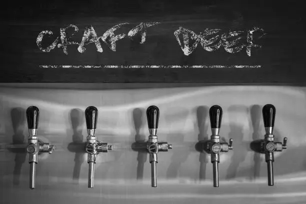 Craft beer tap or beverage faucet (row) in bistro bar and cafe, black and white color tone.