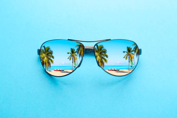 concepto de vacaciones de verano. gafas de sol con playa oceánica y palmeras sobre fondo azul. - gafas de sol fotografías e imágenes de stock