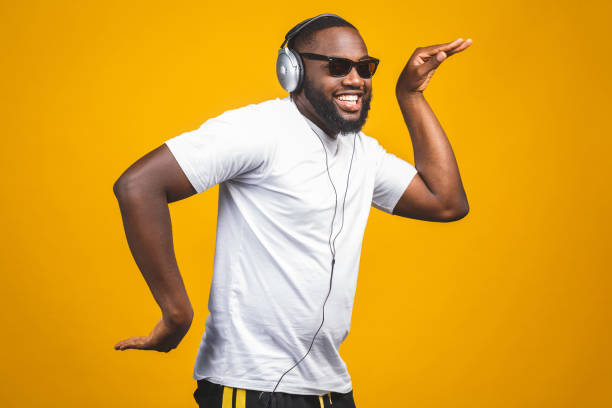 homme afro-américain dans des vêtements occasionnels et des écouteurs écoutant la musique et la danse. - full song photos et images de collection