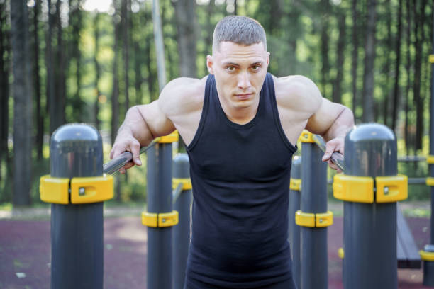 istock Young athletic man doing push-ups on bars outdoors. 1164358504