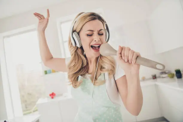 Photo of Portrait of her she nice attractive lovely cheerful cheery glad positive wavy-haired lady maid having fun singing new cool popular hit sauce spoon in light white interior kitchen