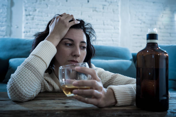 istock Drunk alcoholic depressed woman drinking scotch whiskey spirits alone at home. Feeling hopeless, week and lonely. In People lifestyle, Depression, alcohol addiction, alcoholism and drug abuse concept. 1164363166