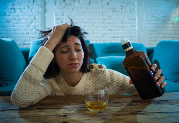 istock Drunk alcoholic depressed woman drinking scotch whiskey spirits alone at home. Feeling hopeless, week and lonely. In People lifestyle, Depression, alcohol addiction, alcoholism and drug abuse concept. 1164363167