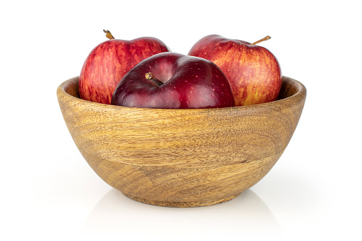 Group of three whole fresh apple red delicious in a big wooden bowl isolated on white background