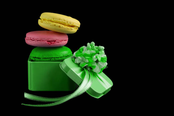 Macaroons box top view. Set of cake in a gift box. Sweet french macaroons cake isolated on black background.