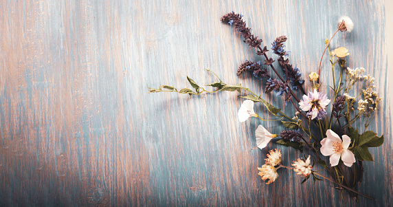 Wild flowers on old grunge blue wooden background (chamomile lupine dandelions thyme mint bells rape).