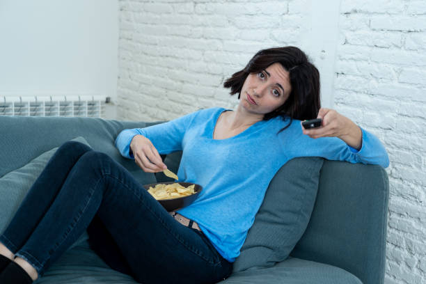 istock Young upset woman on sofa using control remote zapping bored of bad TV shows and programing . Looking disinterested, aloof and sleepless. People, too much bad television and Sedentary lifestyle. 1164367676