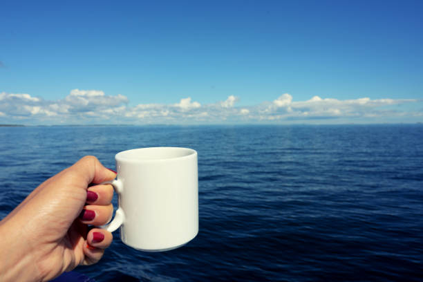 Woman holding black coffee in white cup on sailing boat over sea water holiday summer background