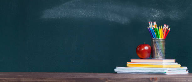 vassoio a matita e una mela sui quaderni sulla scrivania dell'insegnante - blackboard desk classroom education foto e immagini stock