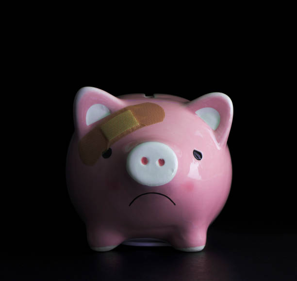 Financial problems, economic depression or savings problem concept. Pink piggy bank with skin plaster bandage on black background. stock photo