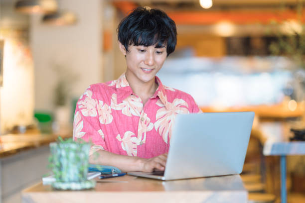 Modern man doing e-banking in cafe A millennial modern man is doing electronic bookkeeping on a laptop in a cafe. He is doing e-banking in a cafe. japan restaurant bill stock pictures, royalty-free photos & images