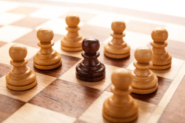 istock black chess pawn surrounded by white chess pawns 1164371880