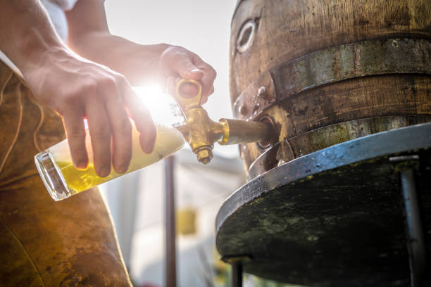 Genuine Bavarian wooden barrel is tapped Bavarian man in leather trousers stabs a wooden barrel of beer in the garden and enjoys the first sip arm hammer stock pictures, royalty-free photos & images