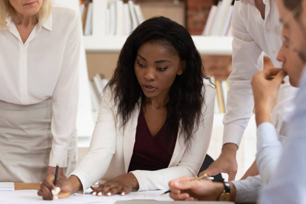 istock Serious african female leader explain paperwork write notes sign paper 1164377514