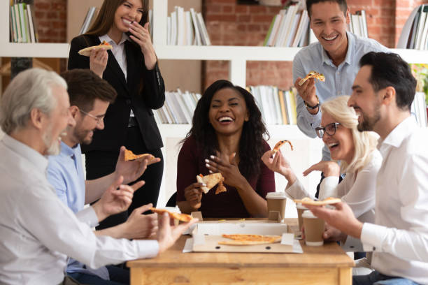 wesoły wielorasowy biuro biznesu ludzie śmiać się dzielić pizza na wynos razem - pizza eating african descent lunch zdjęcia i obrazy z banku zdjęć