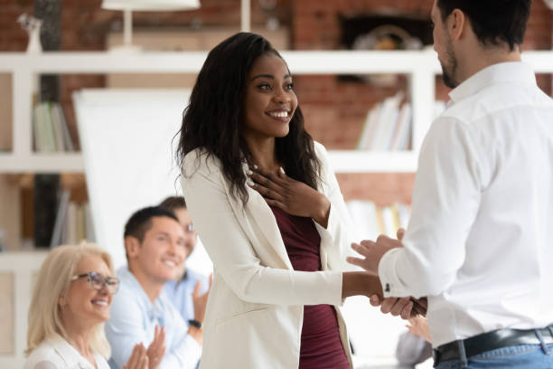Happy proud black female employee get rewarded handshake caucasian boss Happy black female employee get rewarded for professional achievement handshake boss, tolerant male manager shake hand of proud african business woman promote express recognition at work concept achievement stock pictures, royalty-free photos & images