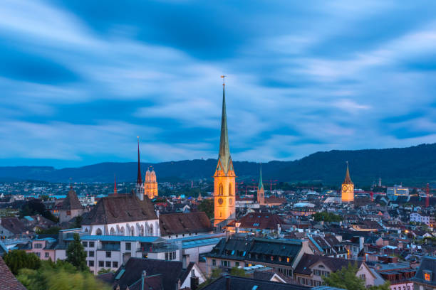 Zurich, the largest city in Switzerland Aerial view of roofs and church towers in Old Town of Zurich, the largest city in Switzerland, during evening blue hour. switzerland zurich architecture church stock pictures, royalty-free photos & images