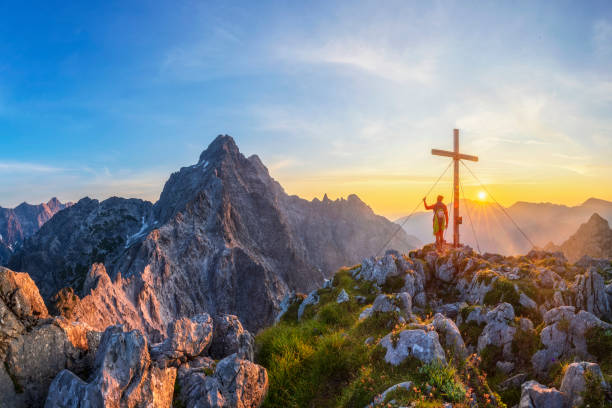 mountain climber at summit cross with glory view to watzmann, berchtesgaden national park - koenigsee imagens e fotografias de stock