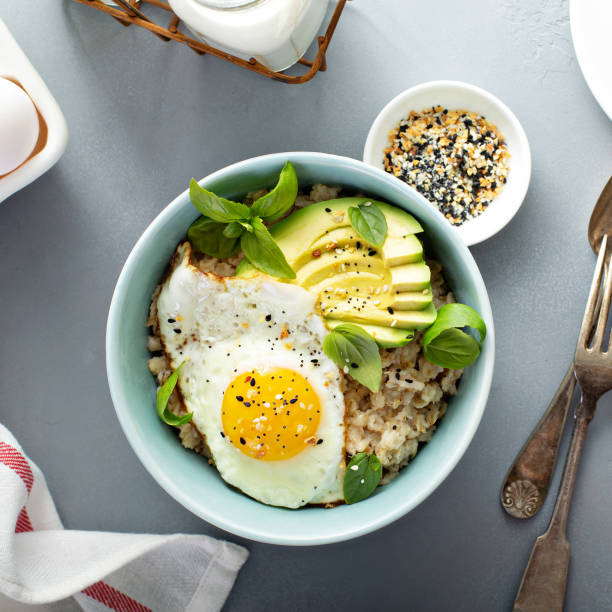 Savory oatmeal with egg and avocado Savory oatmeal with sunny side up egg and avocado for breakfast overhead savory food stock pictures, royalty-free photos & images