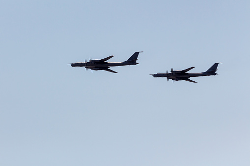 2 Silhouettes flying Russian  turboprop strategic bombers against the sky