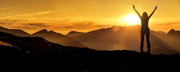 istock Woman in victory pose at sunrise on a mountain peak 1164383034