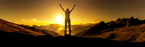 istock Woman in victory pose at sunrise on a mountain peak 1164383036