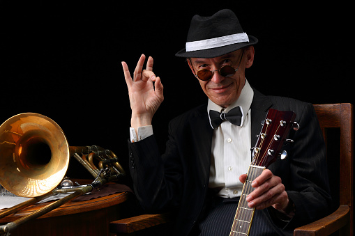 Portrait of an elderly jazz musician in retro style with guitars and trombone