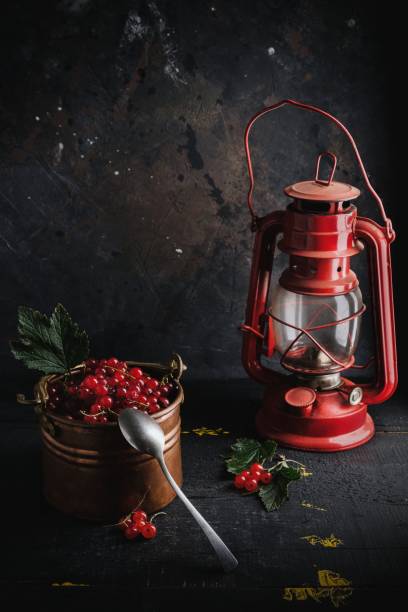 Red currants and leaves in old copper bowl old lantern on dark background stock photo