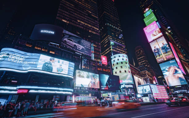 Times Square in New York City at dusk Times Square is a major commercial intersection, tourist destination, entertainment center and neighborhood in the Midtown Manhattan section of New York City at the junction of Broadway and Seventh Avenue. retail digital signage stock pictures, royalty-free photos & images