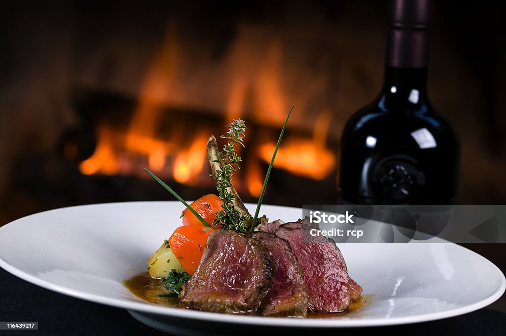 Lamb with a bottle of Wine Lamb chops with vegetables and a bottle of wine in front of a fireplace Wine Stock Photo