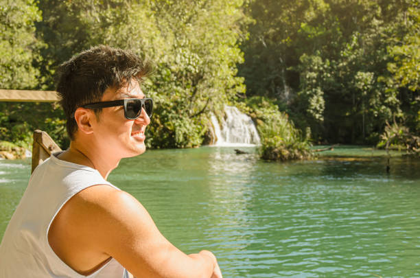 Man enjoying the nature Man wearing sunglasses enjoying the nature. Landscape with a river, some cascades surrounded by trees and green vegetation. Tourist at Bonito MS, Brazil. bonito brazil stock pictures, royalty-free photos & images