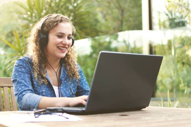 istock Woman using laptop and headphone outdoors in the nature 1164394866