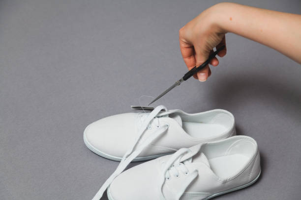 istock Scissors hand cuts label off new white sneakers 1164398447