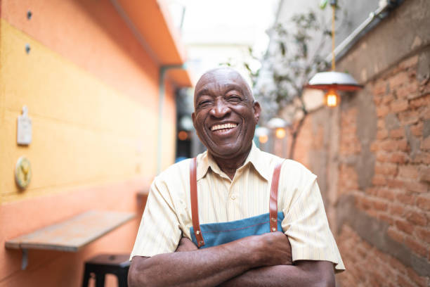 ritratto di cameriere anziano sorridente che guarda la macchina fotografica - 1 serving foto e immagini stock