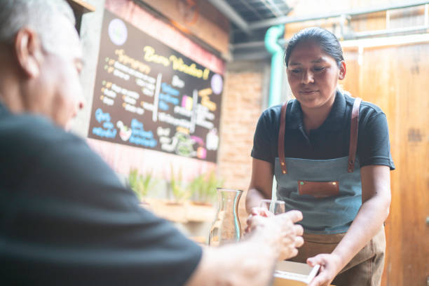 istock Waitress serving drink to a customer at restaurant 1164403675
