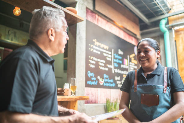istock Customer holding a menu and talking with the waitress at restaurant 1164403969