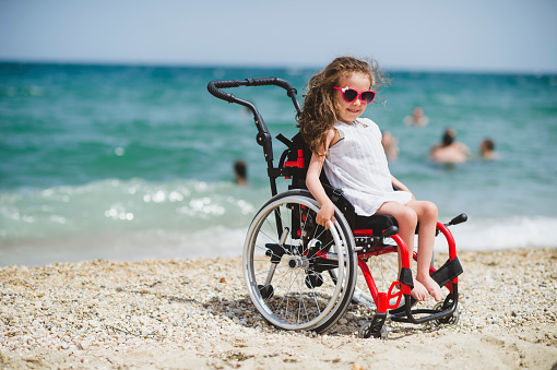 Cute little girl  on the wheelchair by the sea
