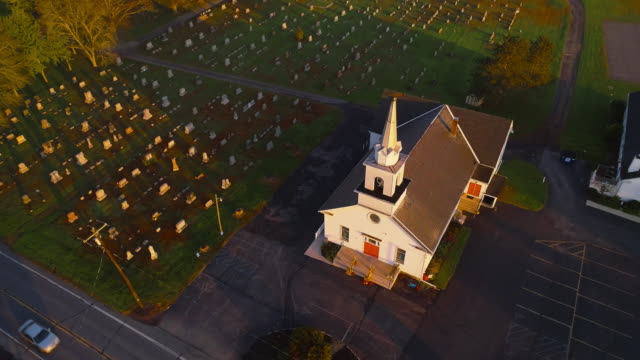 Church and cemetery at sunrise. Brodheadsville, Poconos region, Pennsylvania. Aerial drone video with the forward and tilting-down camera motion.