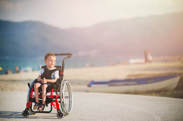 smiling young boy on the wheelchair by the sea - esclerose lateral amiotrófica imagens e fotografias de stock