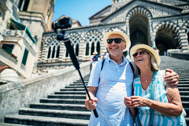 glückliches senior-paar sightseeing amalfi, filmt sich mit moderner kamera - einbeinstativ stock-fotos und bilder