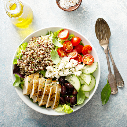 Greek inspired lunch bowl with chicken, quinoa, feta cheese and olives overhead view