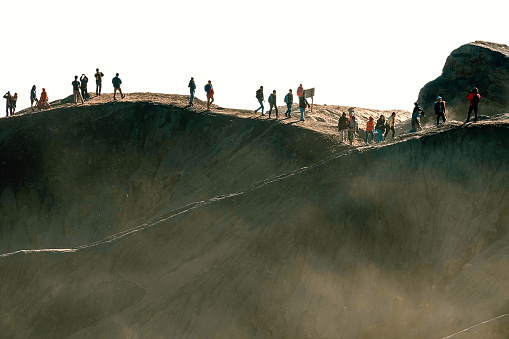 Tourists climbing to Mount Bromo volcano summit at sunrise
