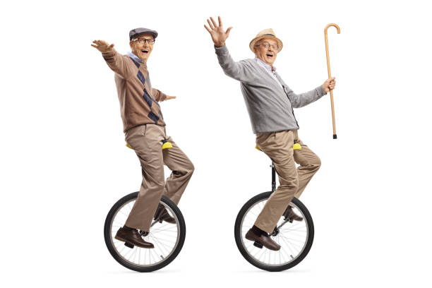 istock Two cheerful senior men riding unicycles and looking at the camera 1164427166
