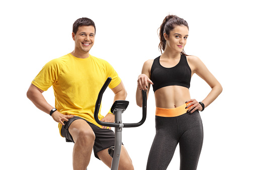 Guy on an exercise bike with a young woman in portswear isolated on white background
