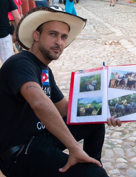 Handsome cowboy showing photos of horseback excursions in Trinidad, Cuba stock photo