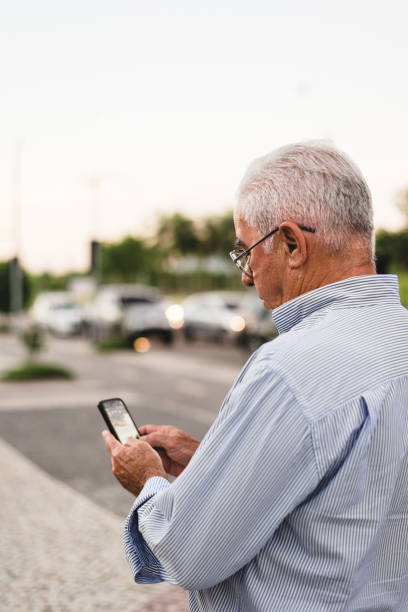 senior man on the streets requesting driver in app - old men car vertical imagens e fotografias de stock