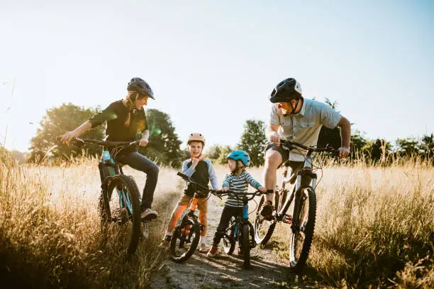 A father and mother ride mountain bikes together with their two small children.  A fun way to spend time together and exercise while on vacation in the Seattle, Washington area.