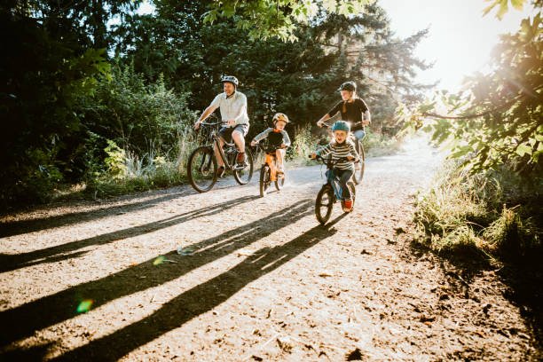 Family Mountain Bike Riding Together on Sunny Day A father and mother ride mountain bikes together with their two small children.  A fun way to spend time together and exercise while on vacation in the Seattle, Washington area. pacific northwest photos stock pictures, royalty-free photos & images